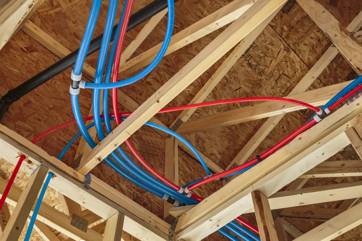 Red and blue PEX water lines run through attic trusses – Newport Beach Navien Tankless Water Heater Installation for Newport Beach, CA homes
